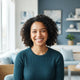 A friendly and diverse parent smiling in a bright, modern room with soft blue accents.