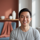 Headshot of a smiling East Asian man in his late 20s to early 30s, looking happy and content.